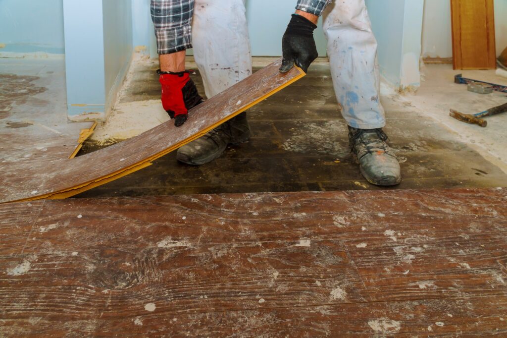 Manual worker disassembling old floor laminated parquet